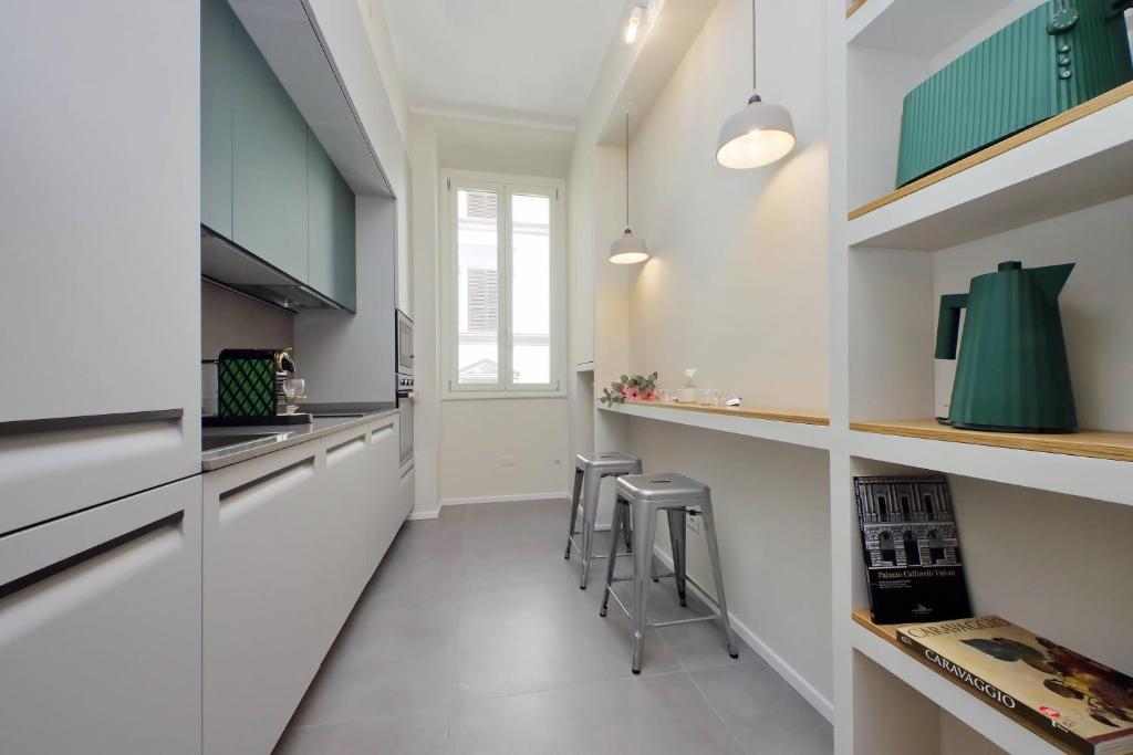 a kitchen with white cabinets and bar stools at Youcomehere - Montebello in Rome