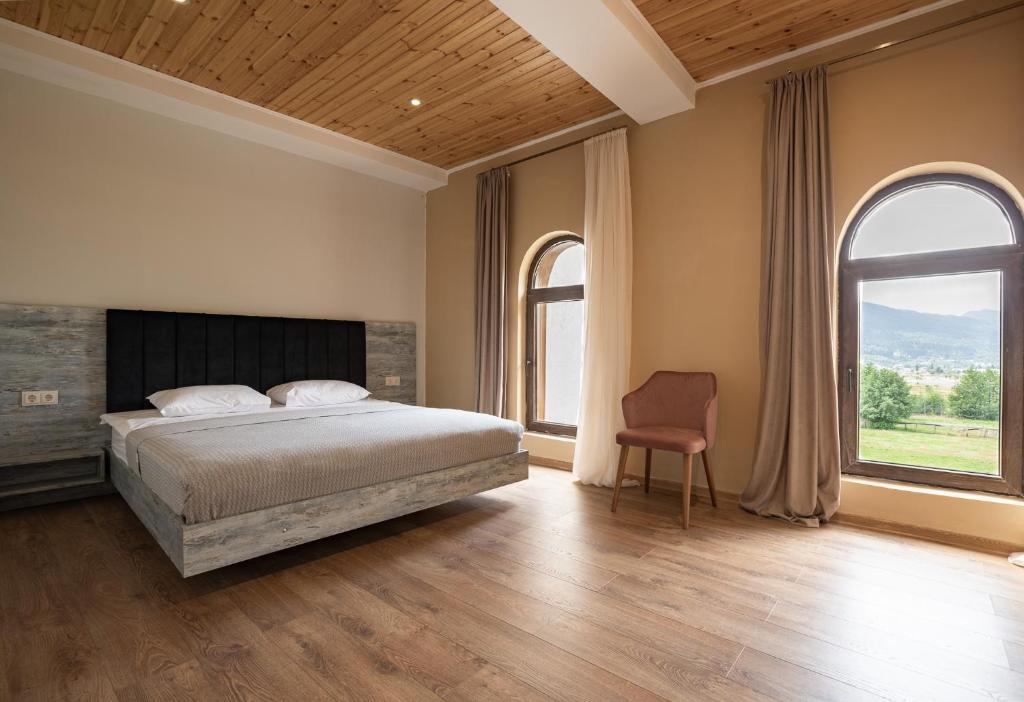 1 Schlafzimmer mit einem Bett, 2 Fenstern und einem Stuhl in der Unterkunft Anne's Hotel in Mestia in Mestia