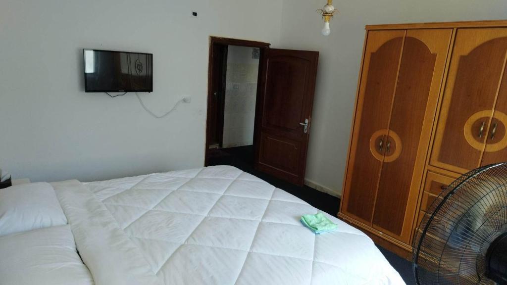 a bedroom with a white bed and a wooden cabinet at City Center Hostel in Jerash