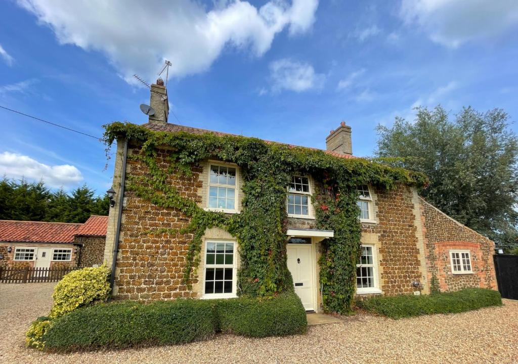 uma casa de tijolos coberta de hera em Ketlam View The Old Coach House em Pentney