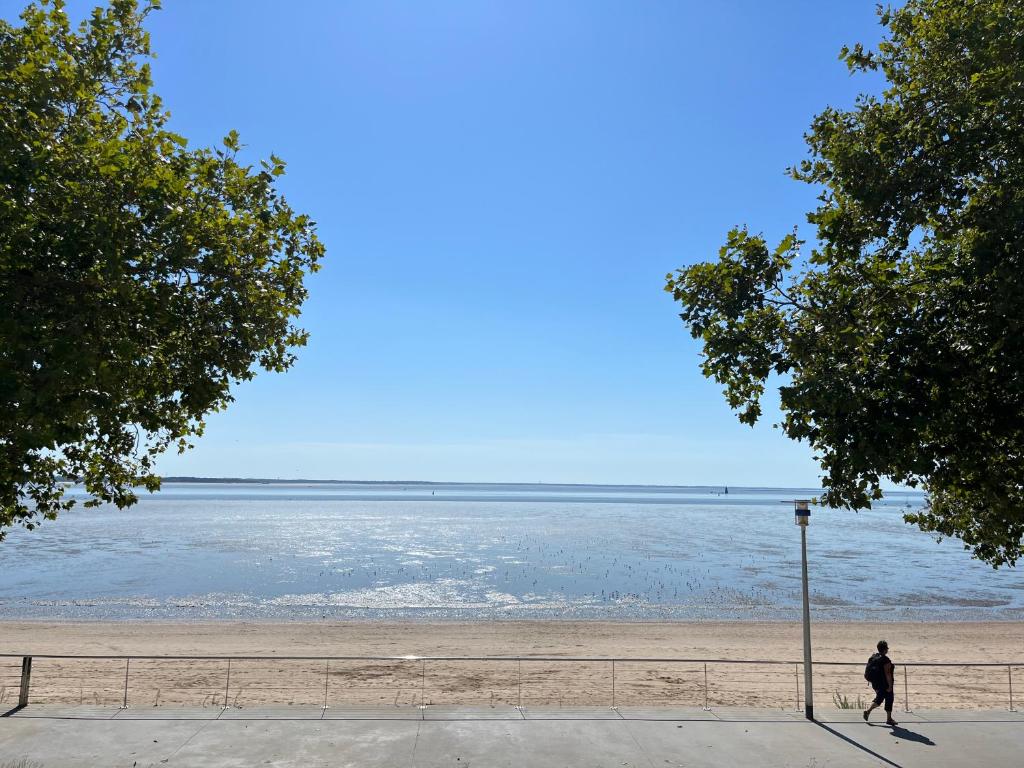 una persona che cammina su una spiaggia vicino all'acqua di Villa Aziliz - Face Mer a Saint-Nazaire