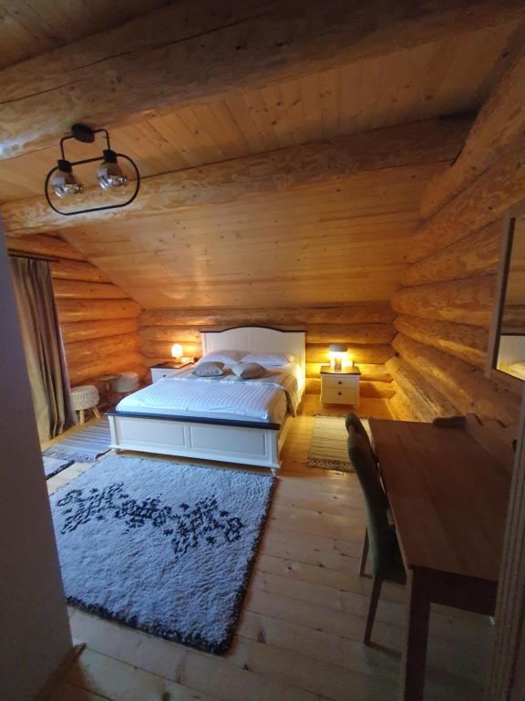 a bedroom with a bed in a log cabin at Căsuța ta de la munte in Broşteni