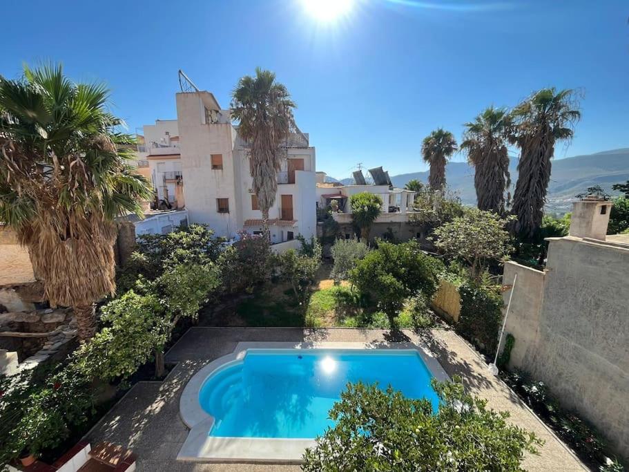 a swimming pool in front of a house with palm trees at Casa De Noor in Órgiva