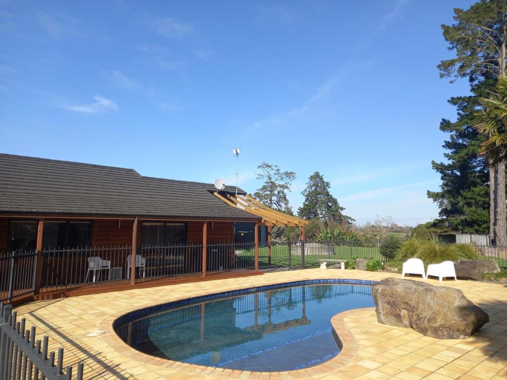 a swimming pool in a yard with a house at Palms on Bruntwood in Tamahere