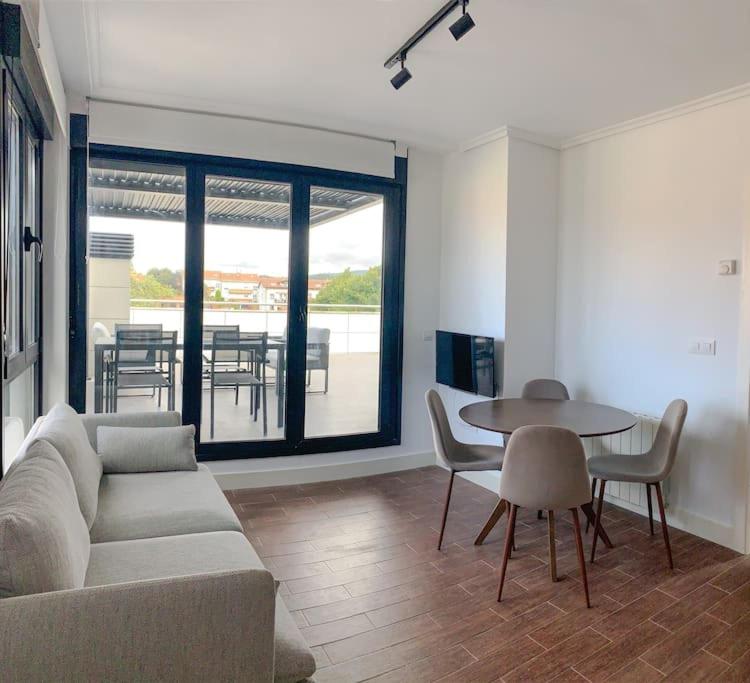 a living room with a couch and a table with chairs at Atico con espléndida terraza in Comillas