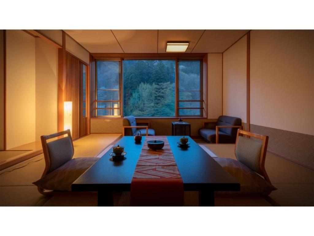 Habitación con mesa, sillas y ventana grande. en Oshuku Onsen Choeikan - Vacation STAY 55578v, en Shizukuishi
