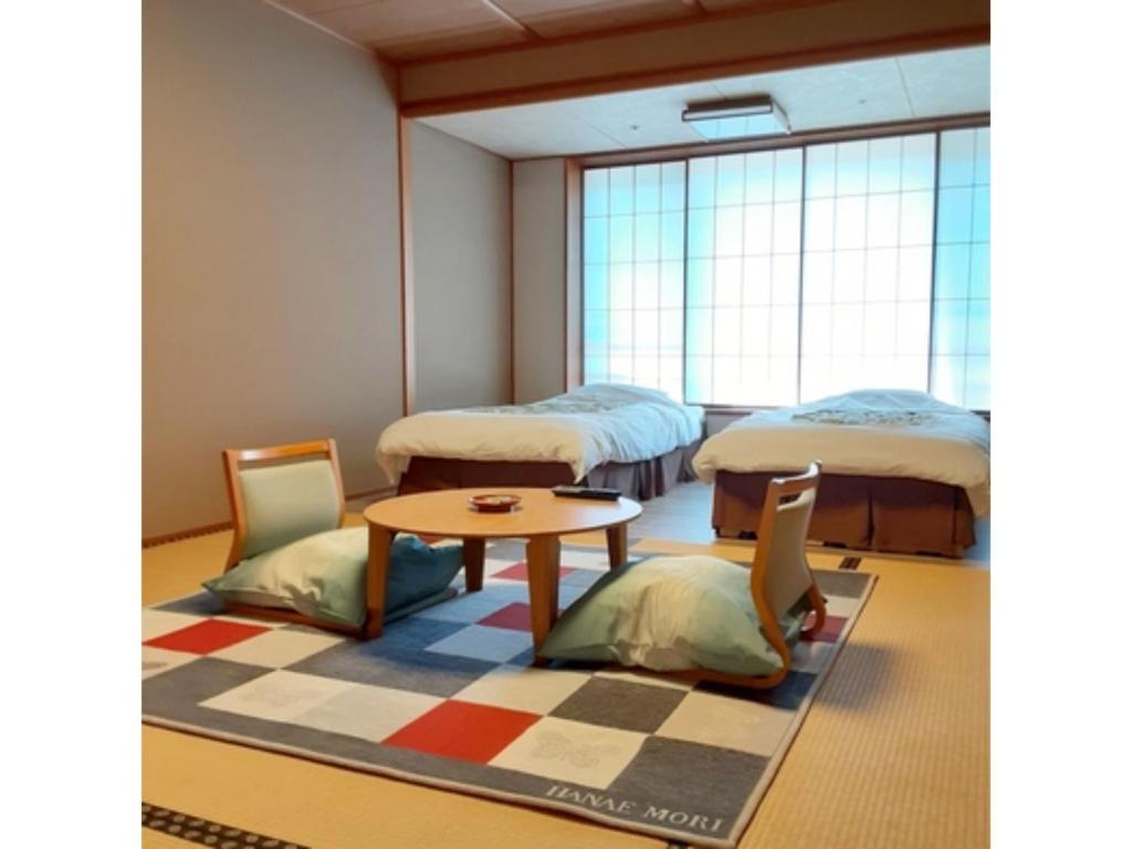 Habitación con 2 camas, mesa y sillas en Oshuku Onsen Choeikan - Vacation STAY 55588v, en Shizukuishi