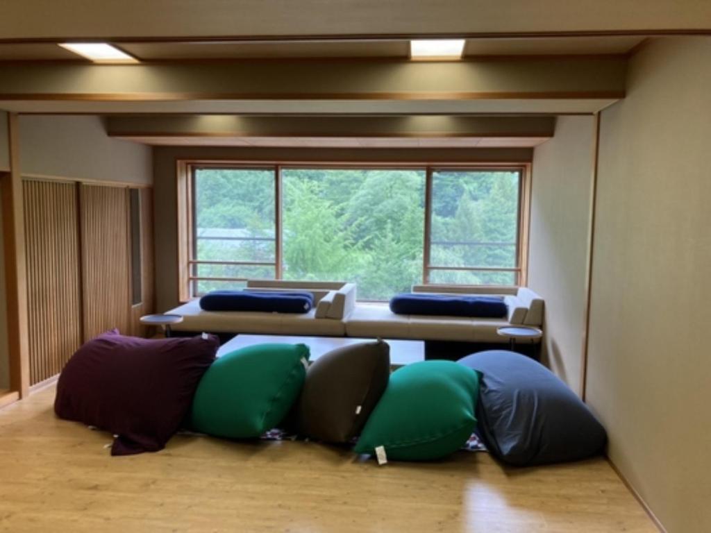 Oshuku Onsen Choeikan - Vacation STAY 55599v في Shizukuishi: غرفة مع عدة وسائد موضوعة على الأرض