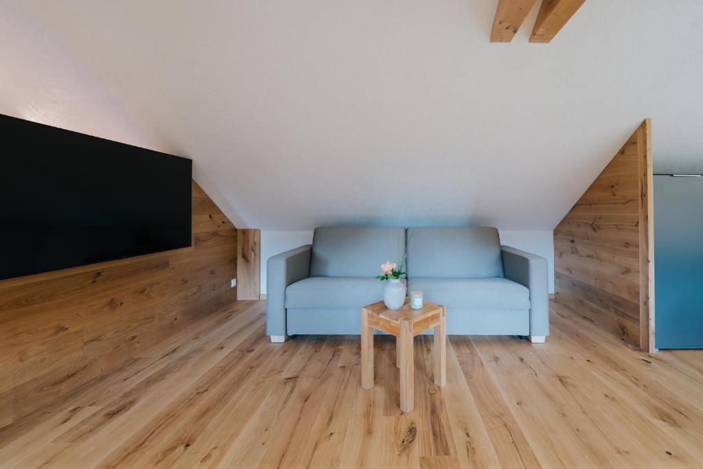 a living room with a blue couch and a tv at Nockventure Ferienhaus Gnesau in Gnesau