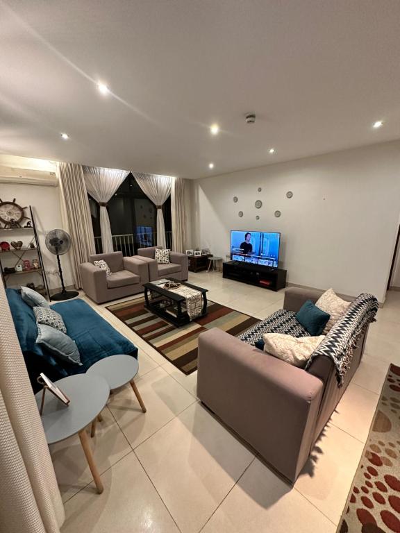 a living room with two couches and a tv at The Perfect Cozy Home For You in Dar es Salaam