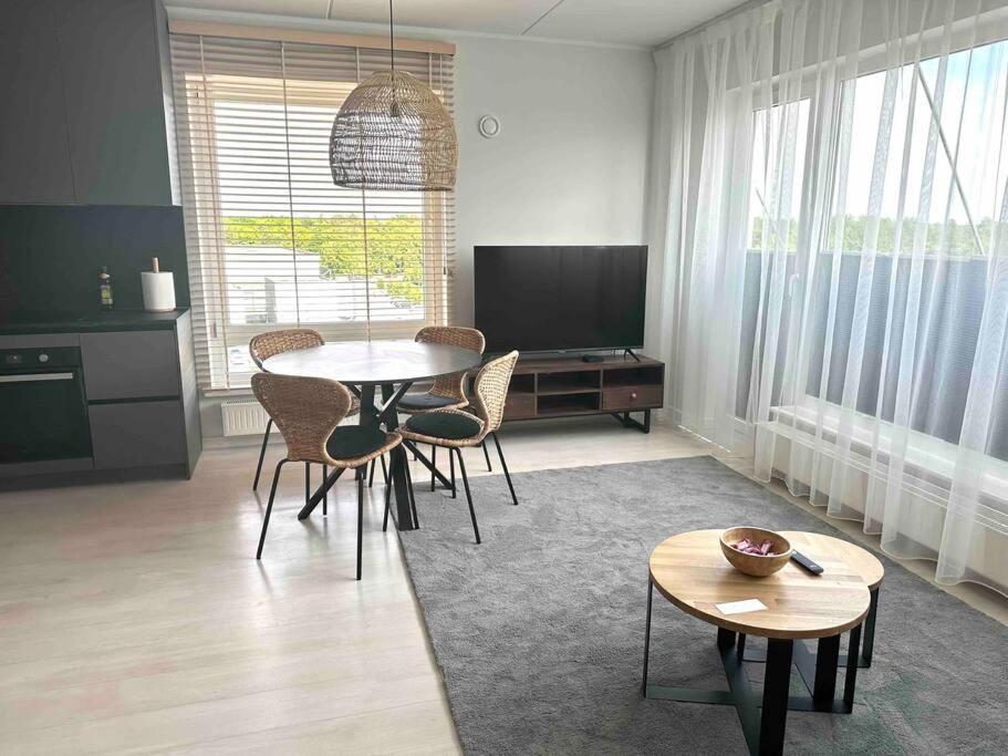 ein Wohnzimmer mit einem Tisch, Stühlen und einem TV in der Unterkunft Cozy apartment near to the beach in Pärnu