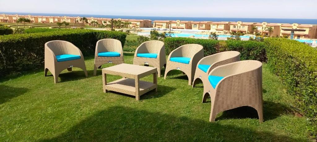 a row of chairs and a table in the grass at Telal Ground Floor 2 bedroms in Ain Sokhna