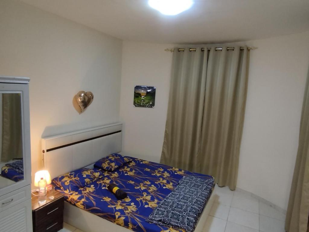 Dormitorio pequeño con cama con edredón azul en Live Like A Family Home Away From Home, en Sharjah
