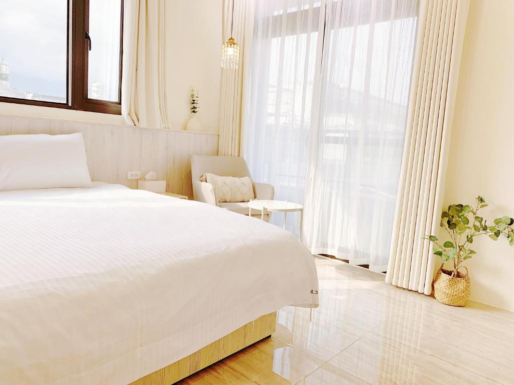 a white bedroom with a large bed and a chair at 光域文旅 in Hualien City