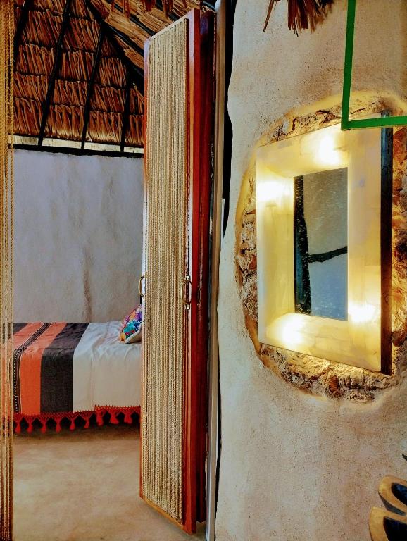 a mirror on a wall in a room with a bed at Hotel y Museo Aldea Maya Toktli Orígenes - Suite Casa Maya 3 Culturas - Alberca, Wifi Starlink, Tour Museo in Izamal