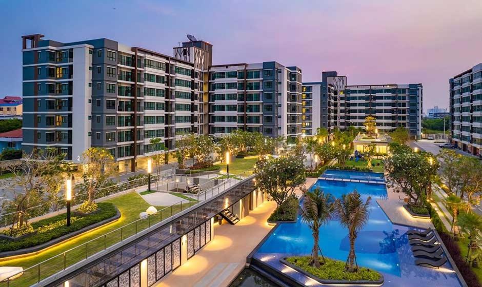 a large apartment building with a pool and palm trees at supalai city resort in Ban Khlong Samrong
