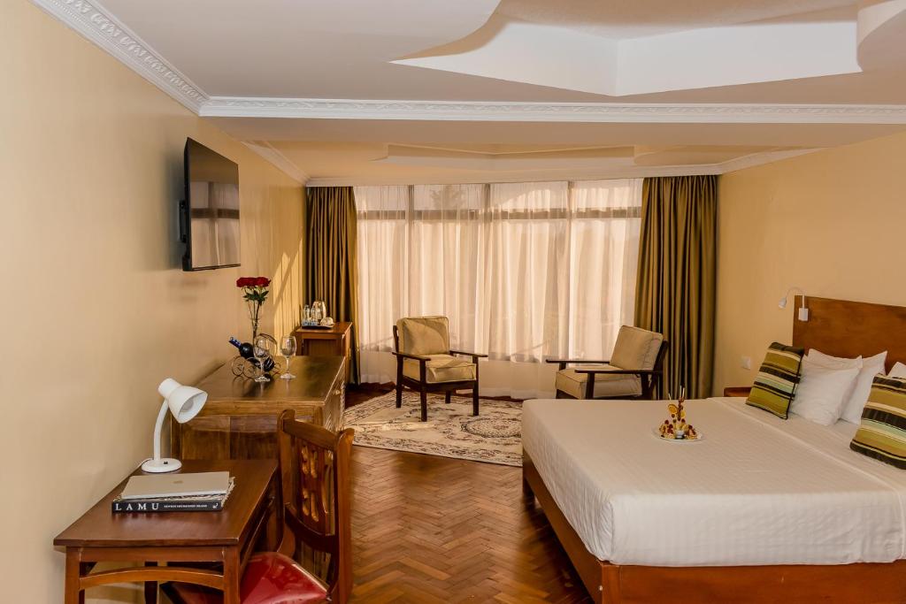 um quarto de hotel com uma cama e uma secretária em The Glacier Hotel Nanyuki em Nanyuki