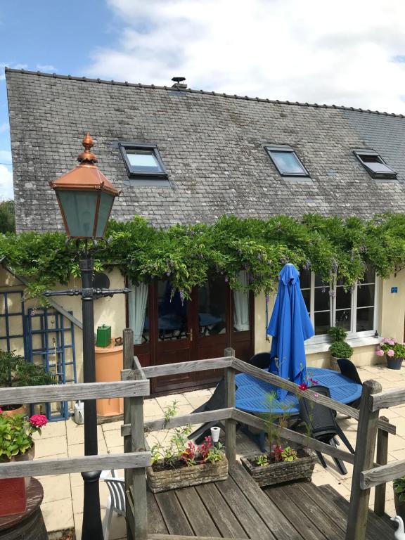 a house with a table and a blue umbrella at Cottage Les Glycines in Javron-Les-Chapelles