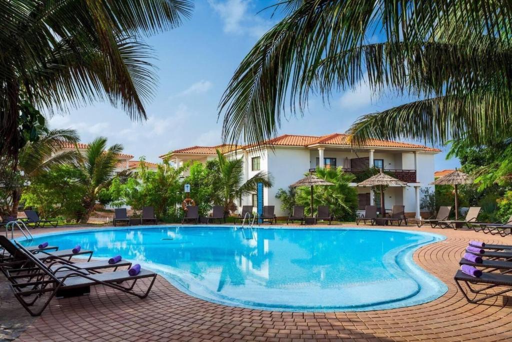 una piscina frente a una casa con palmeras en Tortuga beach lovely 2 bed apartment and gardens, en Santa Maria