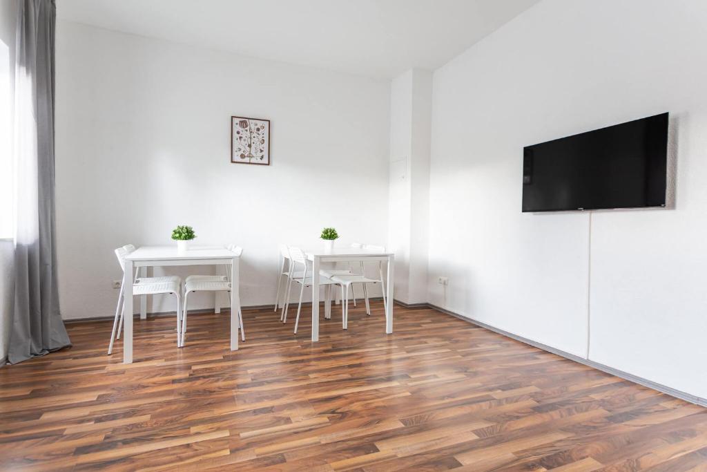 a dining room with white tables and a flat screen tv at T&K Apartments - Duisburg - 3 and 4 Room Monteur Apartments in Duisburg