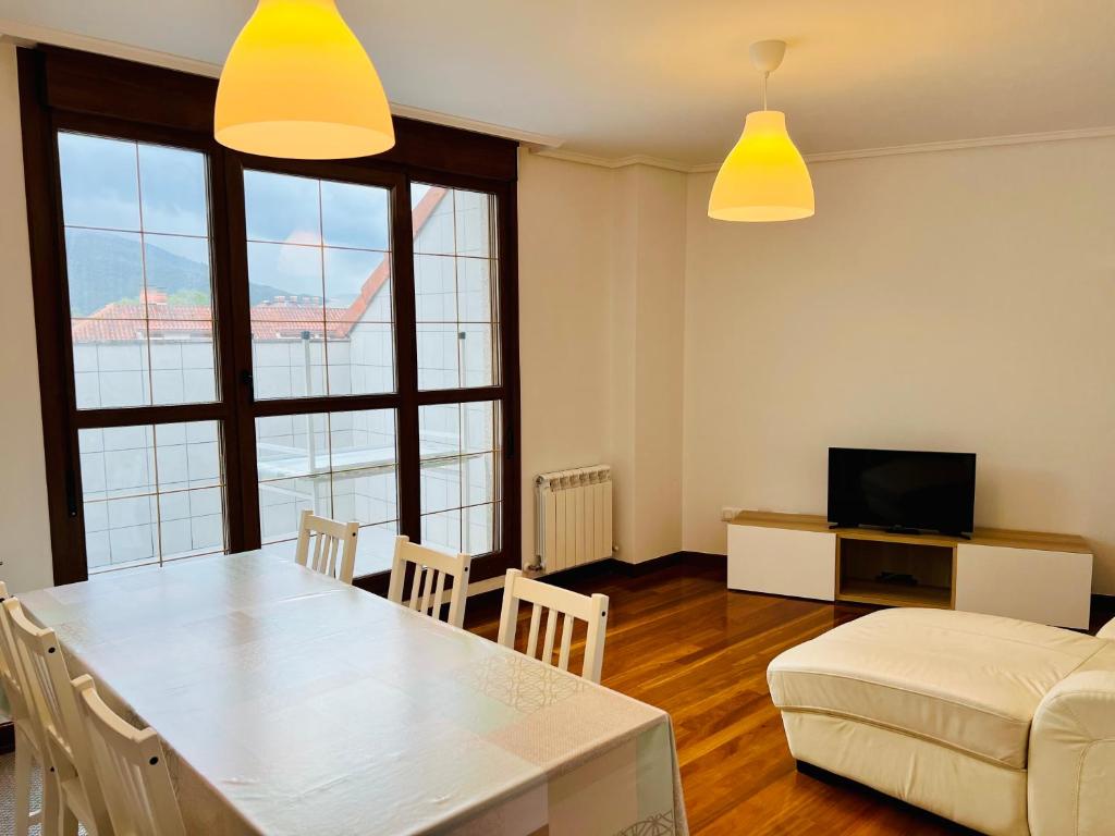 ein Wohnzimmer mit einem Tisch und einem Sofa in der Unterkunft Excelente apartamento con garaje y piscina in Ramales de la Victoria