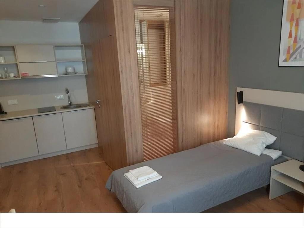 Good Wolska Residence في وارسو: غرفة نوم صغيرة بها سرير ومطبخ