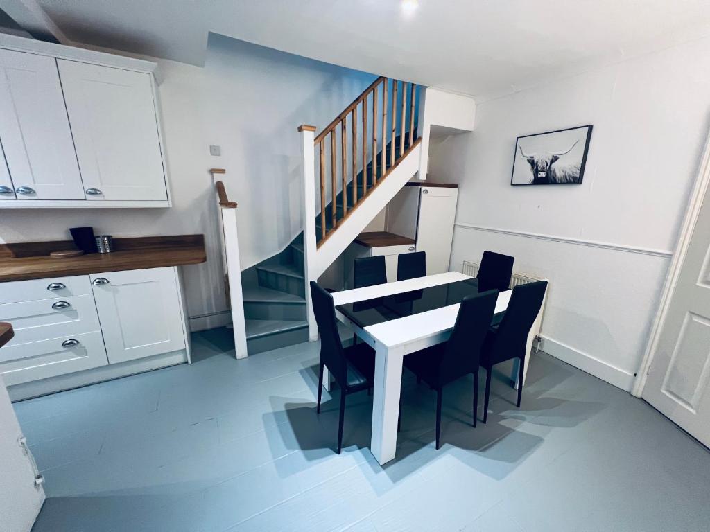 una cocina con mesa y sillas y una escalera en Four bedroom bungalows with private parkings, en Sidcup