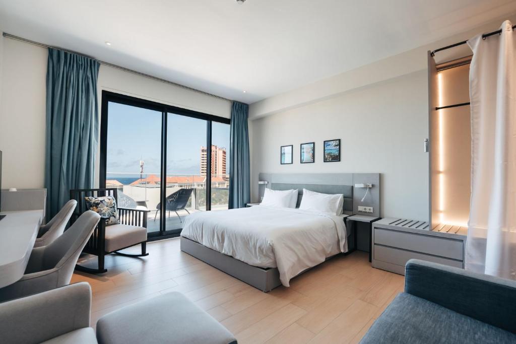 una camera d'albergo con un letto e una grande finestra di Elements Hotel & Shops Curaçao a Willemstad