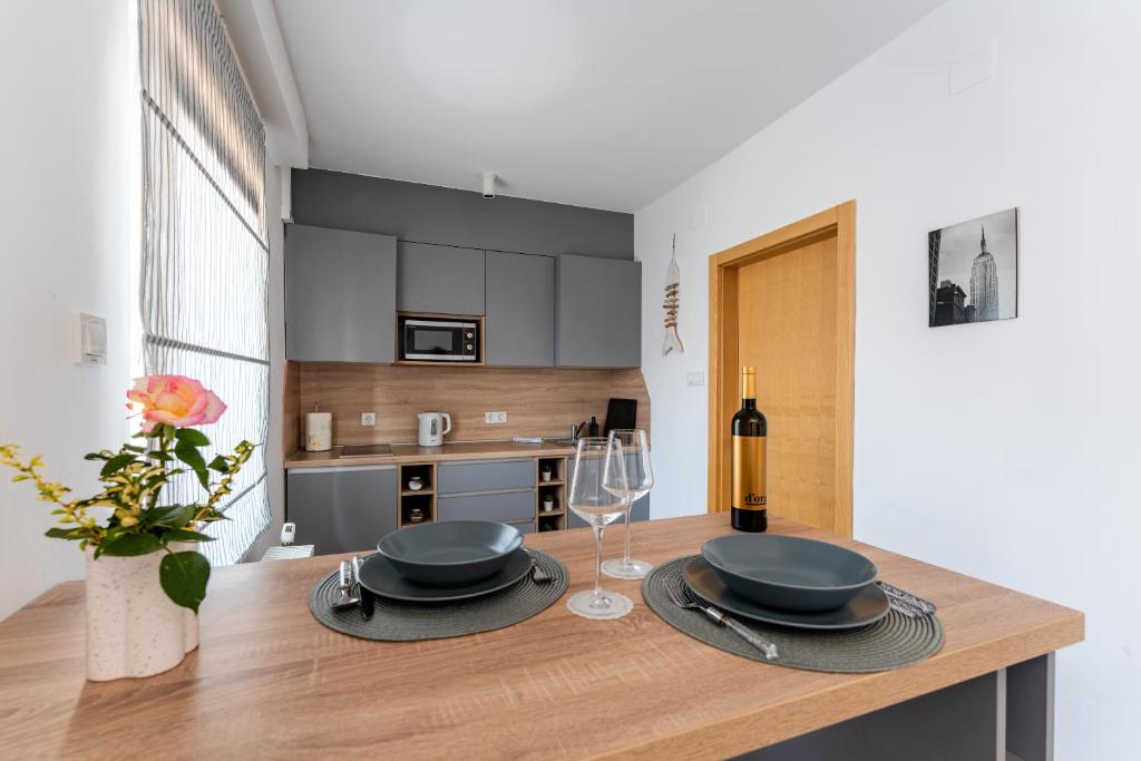 a kitchen with a table with plates and wine glasses at Studio apartman the little Prince in Bjelovar