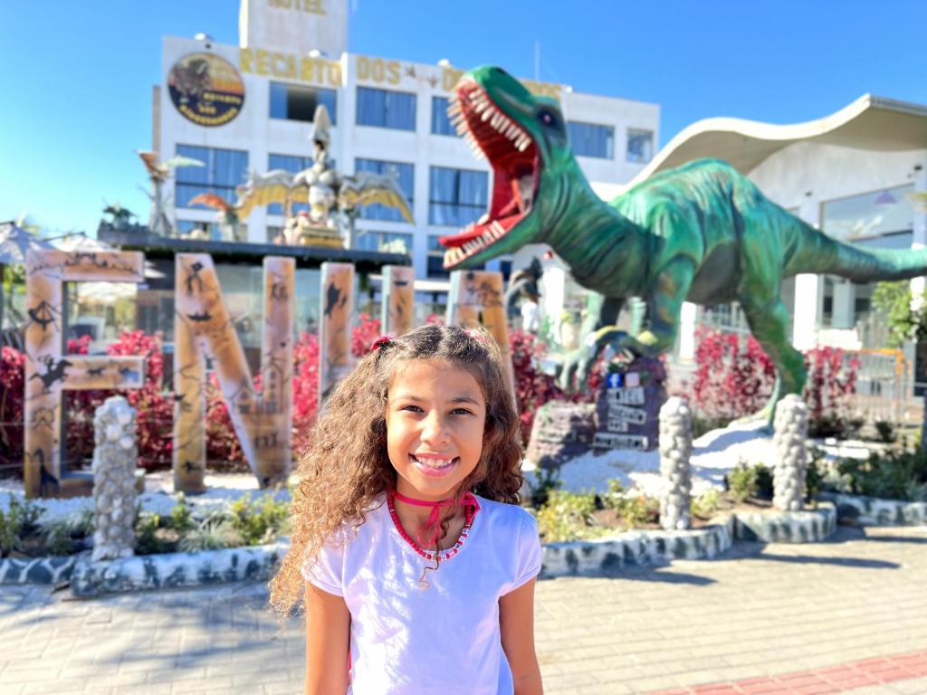 a little girl standing in front of a dinosaur park at Hotel Recanto dos Dinossauros in Penha