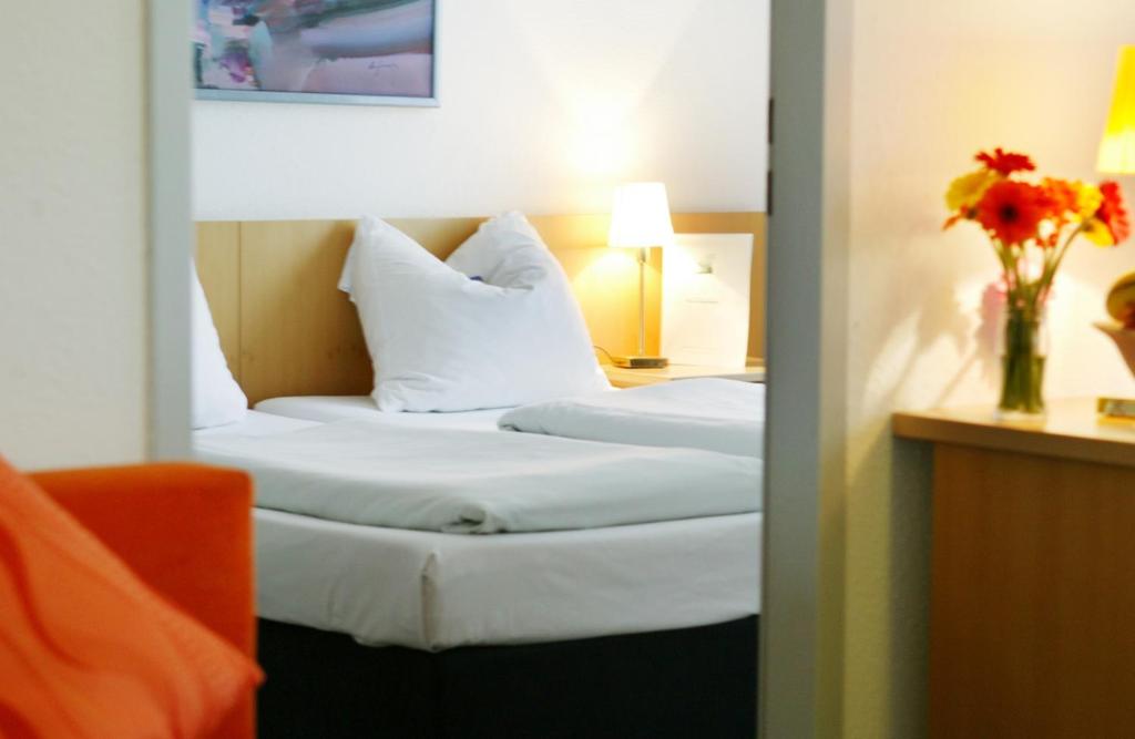 a hotel room with two beds and a vase of flowers at Ariva Boardinghouse Platanenhof in Mannheim