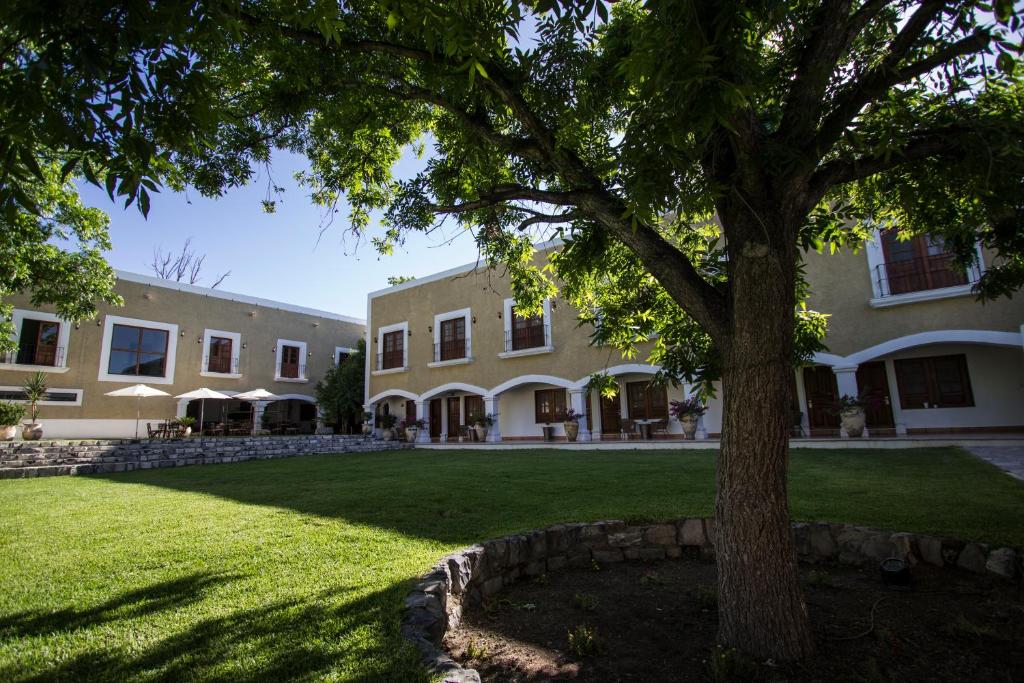a large building with a tree in the yard at La Casona Del Banco Hotel Boutique in Parras de la Fuente