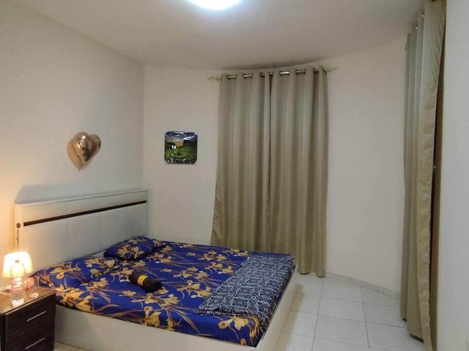 a small bedroom with a bed with a blue blanket at Ultimate Family Apartment 2BHK Sharing with Host in Sharjah