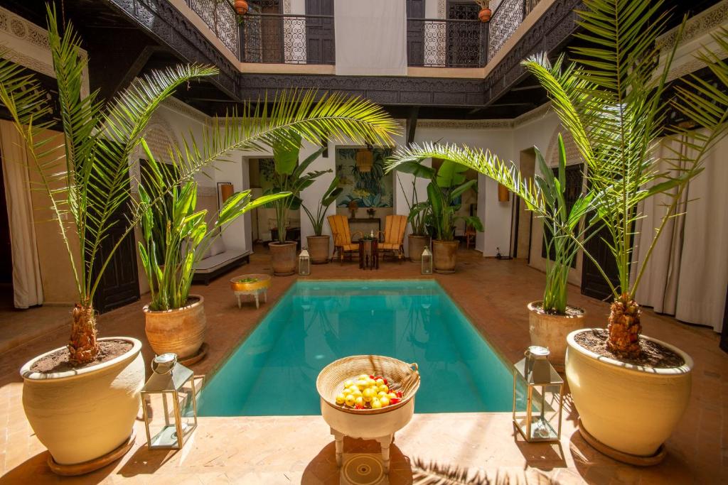 - une piscine dans une pièce ornée de palmiers et de plantes dans l'établissement Riad Bab 54, à Marrakech