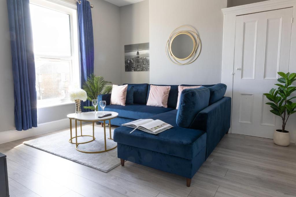 a living room with a blue couch and a table at 2 Bed Apartment by AV Stays Short Lets & Serviced Accommodation Sittingbourne Kent in Kent