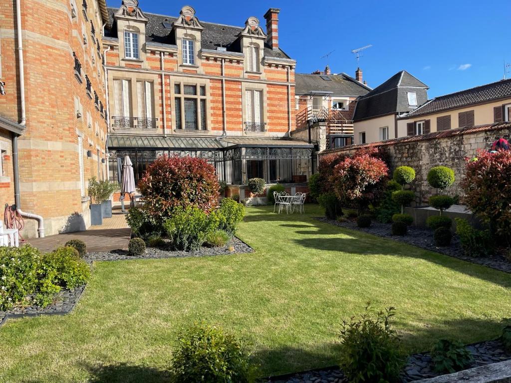a garden in front of a large brick building at Le Jardin d'Hiver in Chalons en Champagne