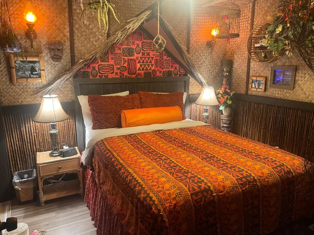 a bedroom with a bed with an orange comforter and two lamps at The Kondo Tiki in Tampa