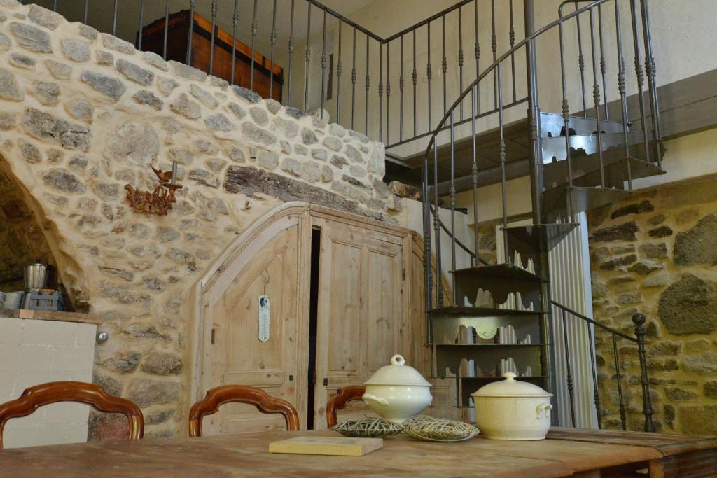 a dining room with a table and a stone wall at La Maison De Marthe in Malleval