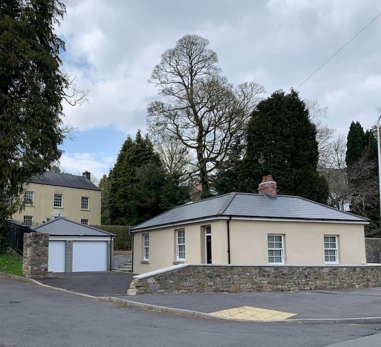 een wit huis met een stenen muur bij Gwaelodygarth Lodge in Merthyr Tydfil