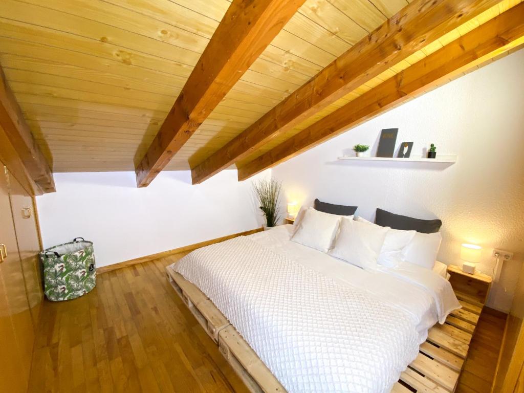 een slaapkamer met een wit bed en houten plafonds bij Ático Dúplex Con Increibles Vistas a La Valle De Incles - Parking Gratis in Incles