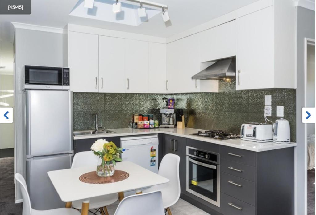 a kitchen with white cabinets and a table and chairs at Albany Modern Private 2 bedroom 2 bathroom with Full Kitchen Netflix in Auckland