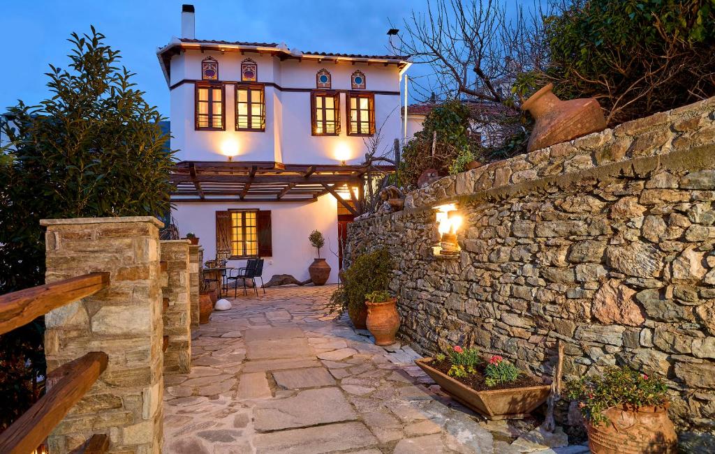 una pared de piedra y una casa con luces. en Thalassoxyla Portaria, en Portaria