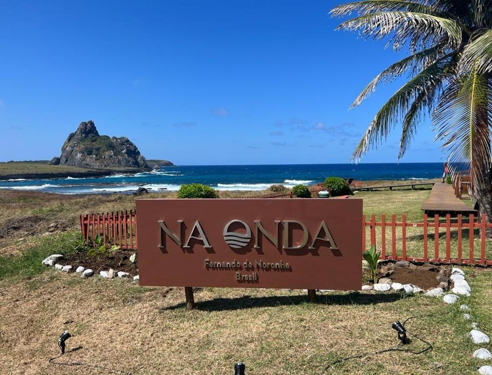 un cartel frente a una playa con el océano en Pousada Naonda en Fernando de Noronha