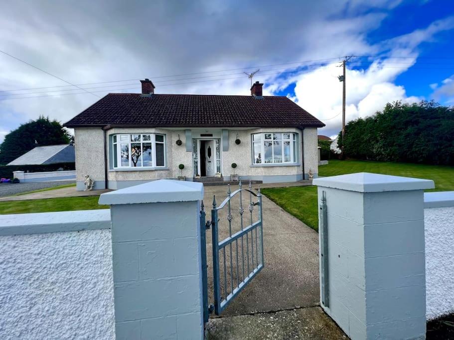 a white house with a gate in front of it at The Myles' Self-Catering Cottage - 4 Stars in Greencastle