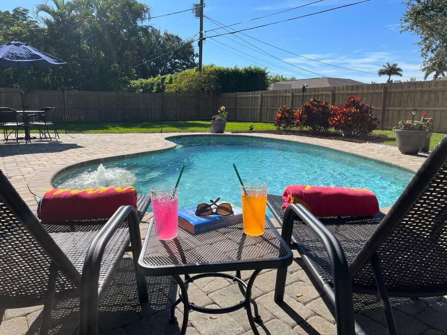 a table with two drinks on it next to a pool at Southern Charm meets sunny FL fun! Home with pool and central to everything. in Cape Coral
