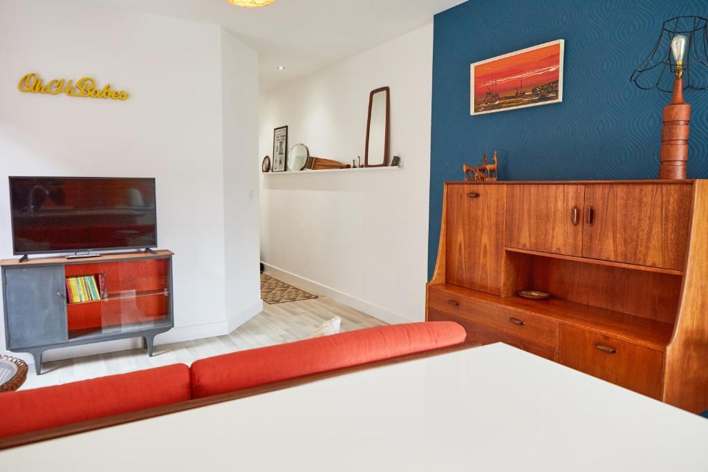 a living room with a red couch and a tv at Binks - Seafront 1 bed first floor apartment in Cleethorpes