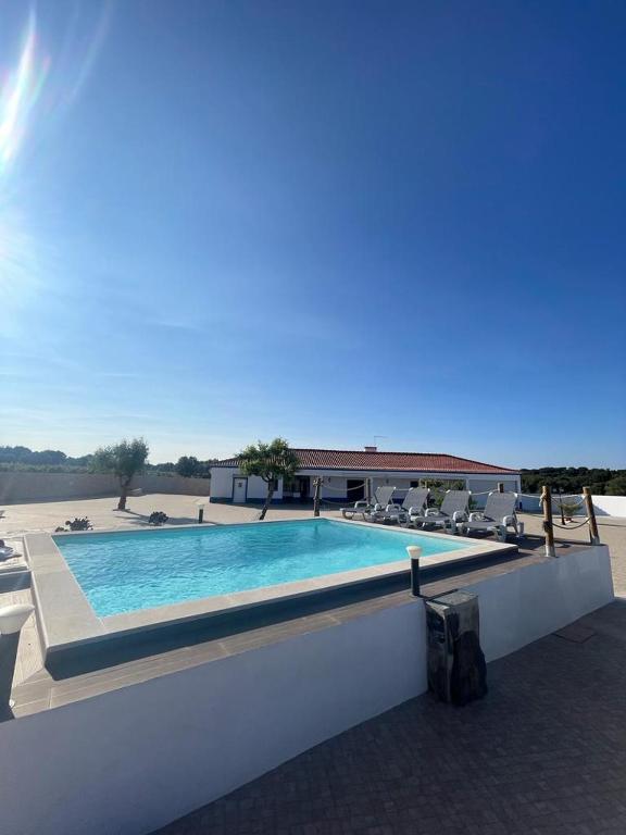 a swimming pool with chairs and a building at Alojamento do Monte in Estremoz
