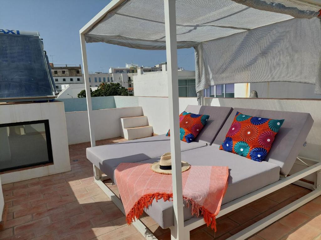 a couch under an umbrella on a roof at Cosy Terrace House - design, comfort, micro-pool, top location in Olhão in Olhão