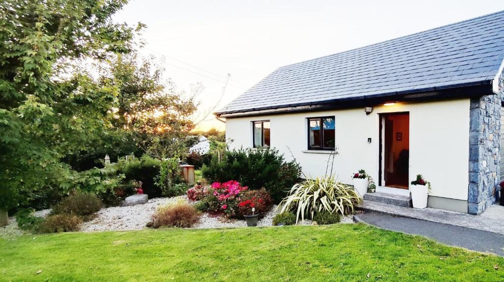 a white house with a garden in front of it at Butterfly Guesthouse - Entire Home within 5km of Galway City in Galway