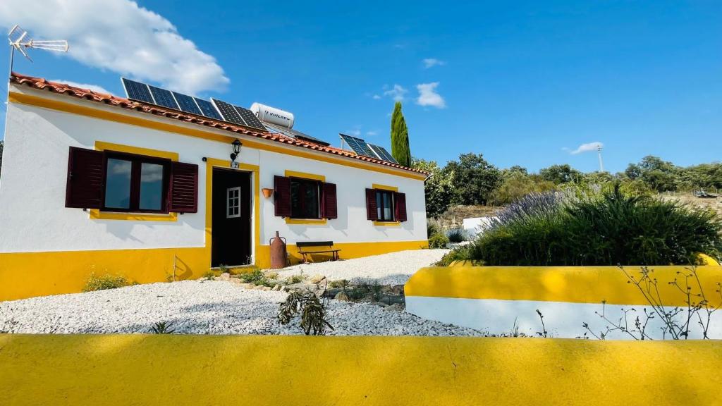 una casa amarilla y blanca con paneles solares. en Lugar d´vagar, Vale Serrão, Castelo de Vide, en Castelo de Vide